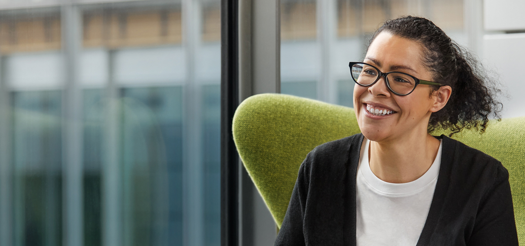 Karen sentada em uma cadeira verde. Ela sorri.