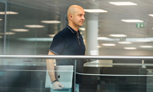 Roberto caminhando enquanto segura um laptop.