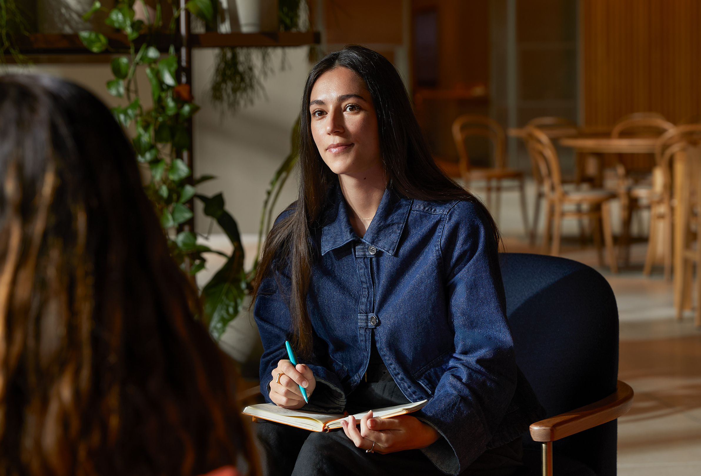 An Apple team member at a table in a common area, speaking to a colleague.