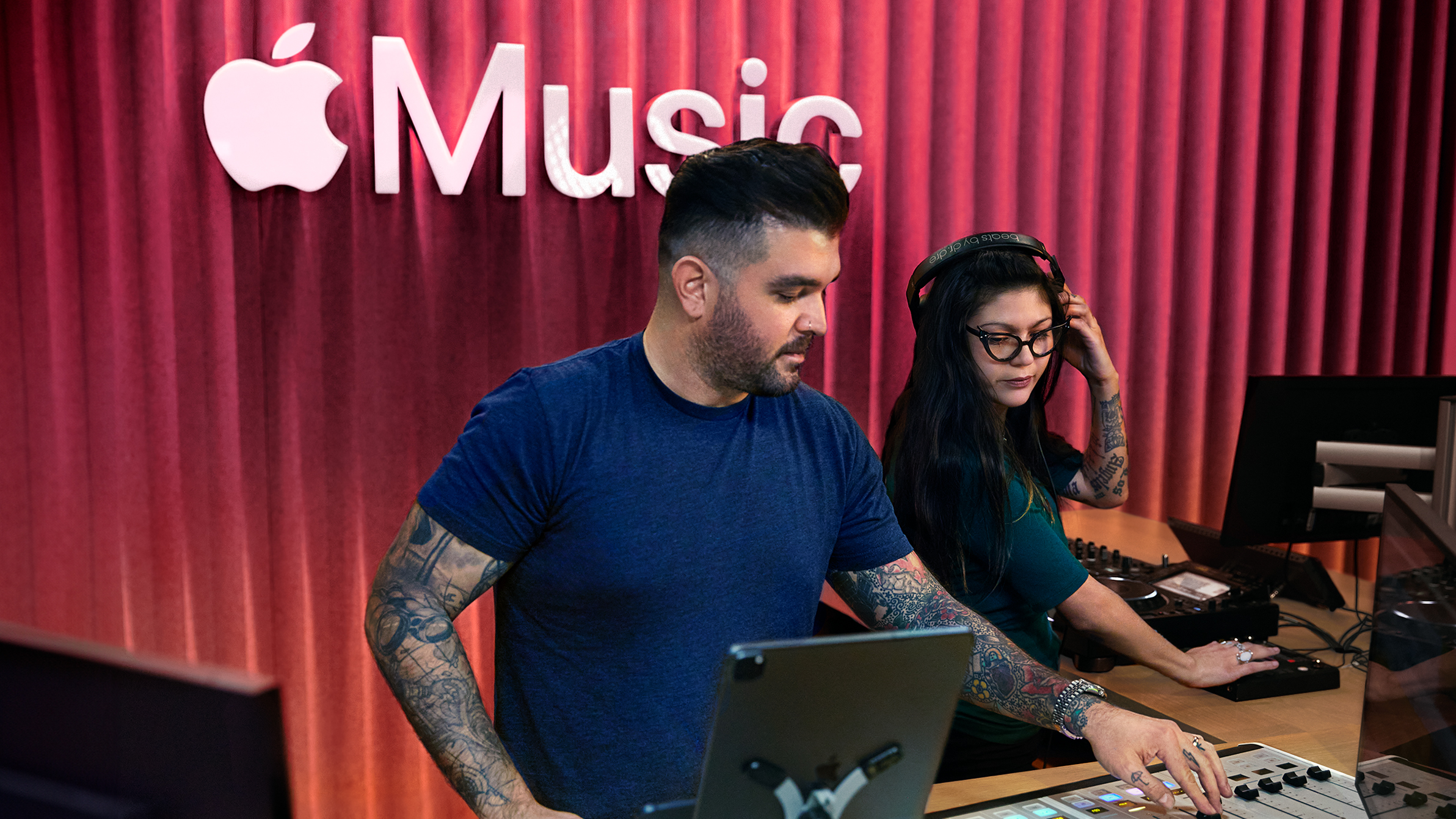 Twee Apple medewerkers bedienen een audiomengpaneel in een Apple Music-studio.
