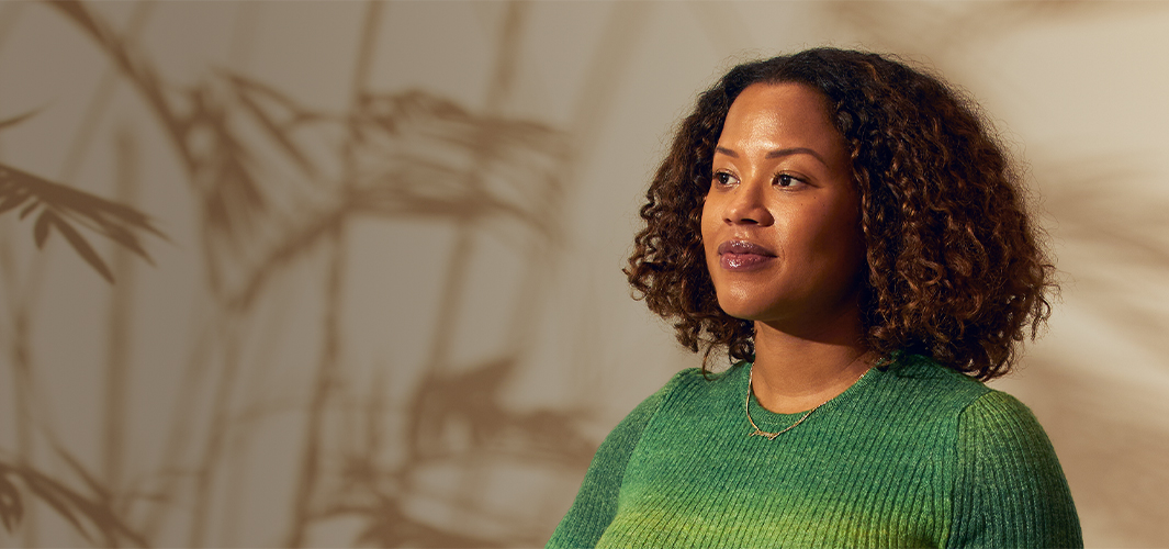 Sydney staat in een binnenruimte en kijkt zelfverzekerd naar rechts.