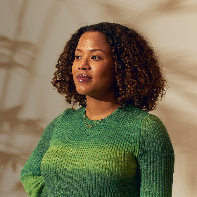 Sydney staat ergens binnen en kijkt zelfverzekerd naar rechts.