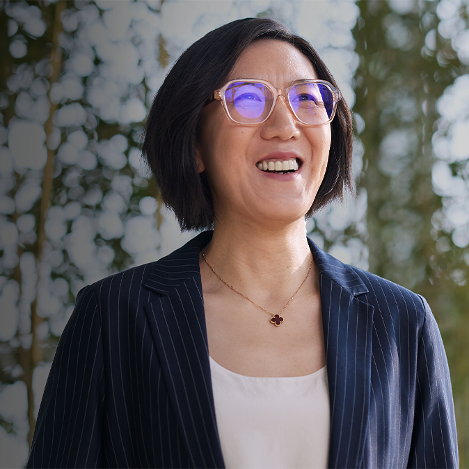 Ella ยิ้มและมองดูข้างบน ด้านหน้าของเธอเป็นสวนต้นไม้บนผนัง