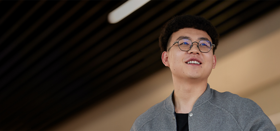 Jason ยืนอยู่ในอาคาร กำลังยิ้มและมองไปทางขวา