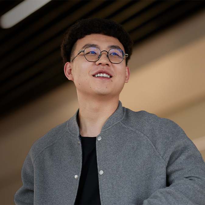 Jason ยืนอยู่ในอาคาร กำลังยิ้มและมองไปทางขวา