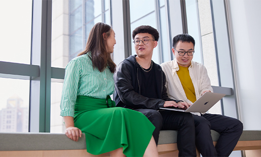 Jason นั่งอยู่ระหว่างเพื่อนร่วมงาน 2 คน ด้านหลังเป็นหน้าต่างสูงจากพื้นถึงเพดาน เขากับพูดอยู่และมือถือ MacBook ไว้