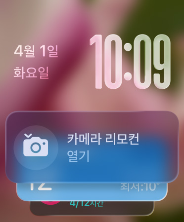 화면 하단에 카메라 리모컨 위젯이 나타나고, 오른쪽 상단에는 반투명 시간 숫자, 왼쪽 상단에는 날짜가 표시된 모습