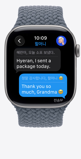 ‘실시간 번역’ 기능이 iMessage의 언어를 영어로 바꿔주는 모습을 보여주는 스페이스 그레이 알루미늄 케이스 색상의 Apple Watch Series 11, 그리고 앵커 블루 색상 브레이드 솔루 루프