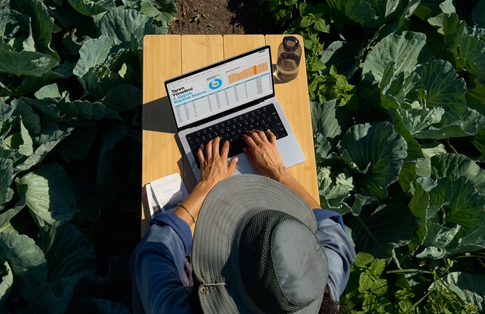 Bir kullanıcı nano-texture ekrana sahip MacBook Pro’yu açık havada kullanıyor, ekran parlamasındaki azalma gösteriliyor