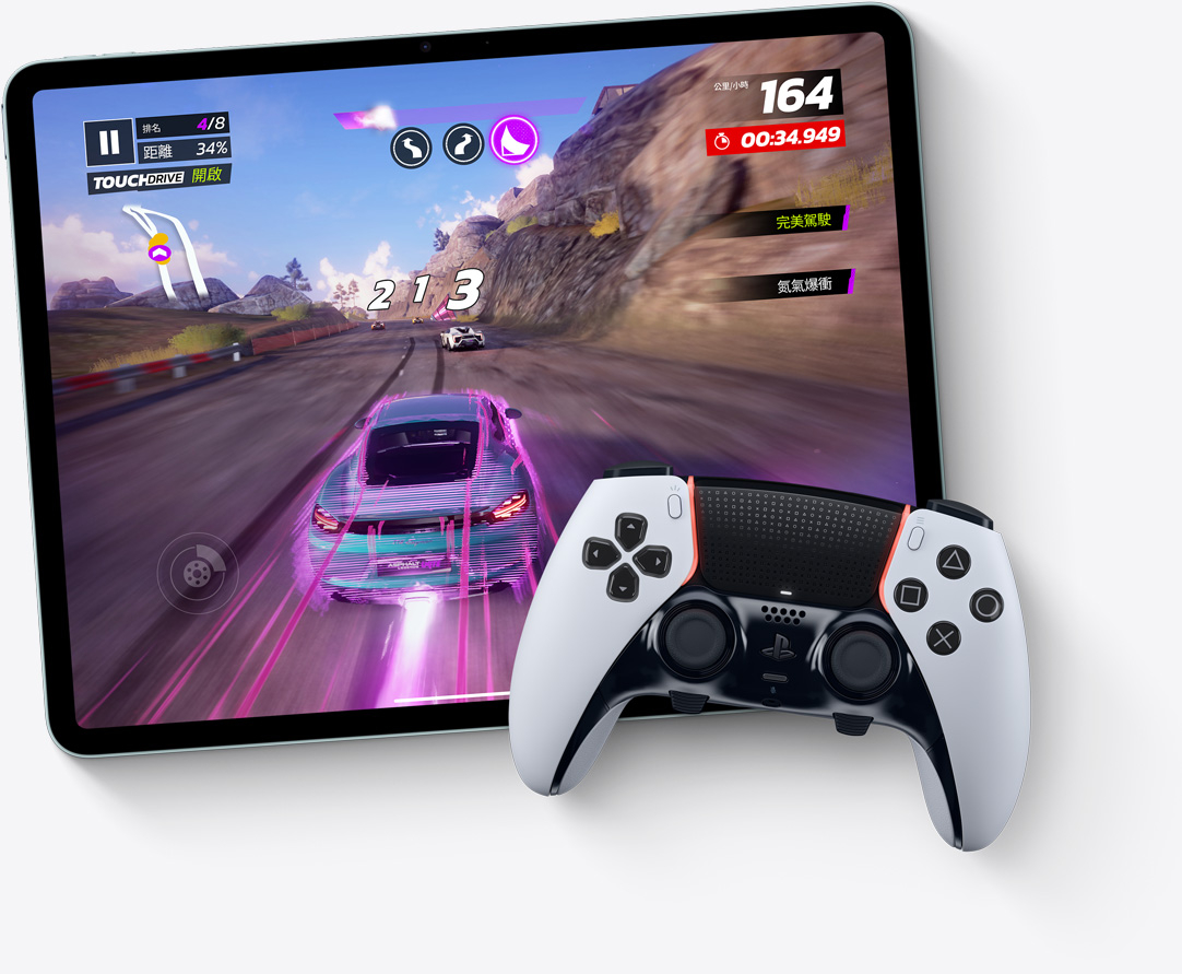 橫向放置的 iPad Air，螢幕顯⽰電玩遊戲狂野飆⾞：傳奇⼤集結的畫面，旁邊有 PlayStation 控制器