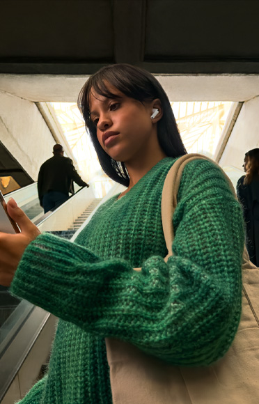 Persona ar AirPods Pro 3 ausīs skatās iPhone