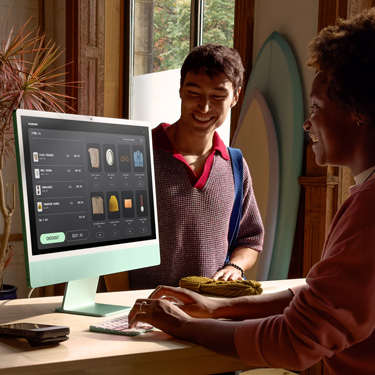 Dans une boutique de surf, une personne derrière le comptoir traite une transaction sur iMac.