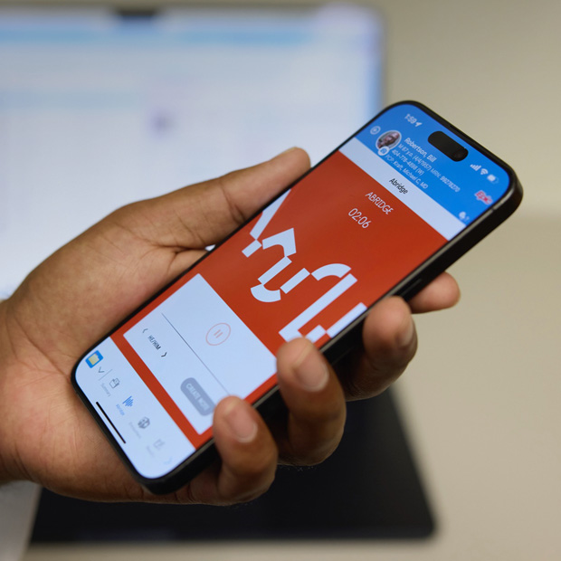 En hand som håller en iPhone med appen Abridge som skapar journalanteckningar utifrån samtal mellan patienter och läkare.