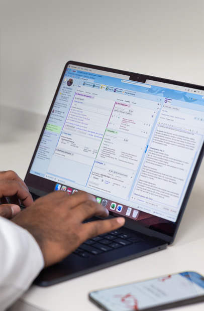 En vårdgivare som studerar elektroniska patientjournaler på en MacBook Pro.