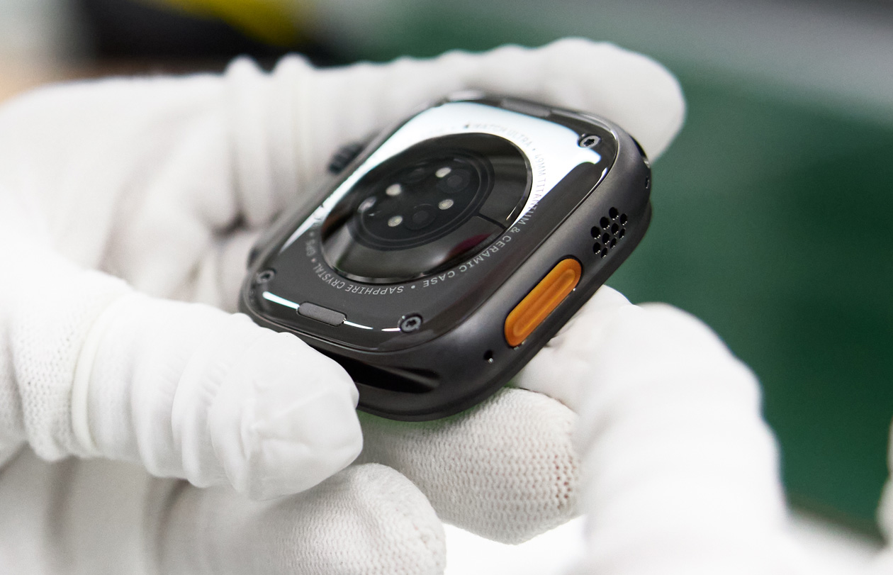 Gloved hands hold the base of an Apple Watch backside up